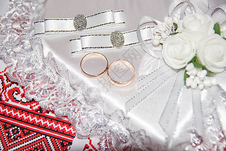 结婚戒指躺在枕头上 以心脏的形式出现 乌克兰婚礼刺绣特写新娘戒指珠宝垫子蕾丝传统软垫白色首饰金子图片