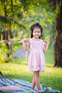 可爱小女孩的肖像 在公园里站着季节孩子粉色女孩儿童花园微笑生活绿色头发图片