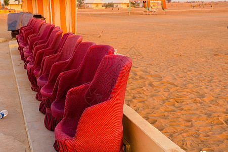 沙漠帐篷近距离拍摄红色泥土甘蔗椅子沙发和小黄砖墙 让参观者在表演时坐席 背景是沙漠沙子旅行游客营地壁画娱乐座位蓝天旅游乐趣公路背景