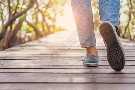 人类在通往自然的小型木桥上行走 用太阳耀斑漫步男性小路女士成人地面裙子男人团体女性牛仔裤图片