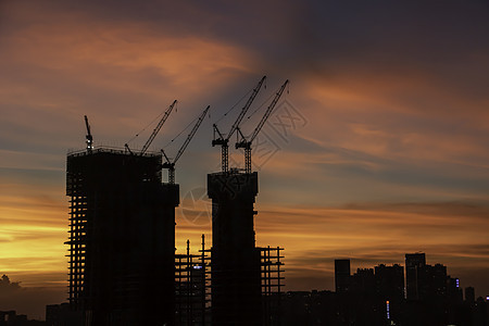 日落时建筑工地城市工作橙子商业工程起重机太阳工业建筑学天空背景图片