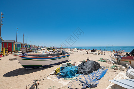 西班牙安达卢西亚Huelva渔村La Antilla捕鱼村典型的渔民小屋灯柱红色展位渔具海滩天空沐浴者鸟类海鸥蓝色图片