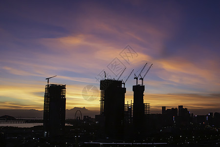 日落时建筑工地工业起重机太阳建筑学橙子工程城市天空商业工作背景图片