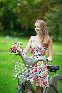 在农村骑自行车的漂亮女孩在乡下女孩白色闲暇公园女士假期绿色花朵裙子图片