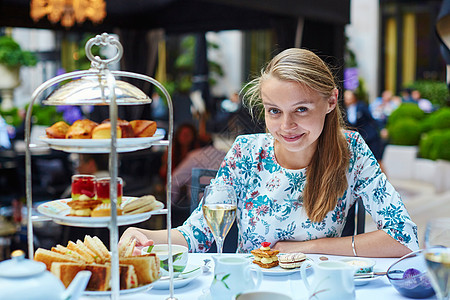 年轻女性享受下午茶叶蛋糕盘子玻璃派对英语金发自助餐甜点蛋糕架女孩背景图片