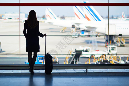 在国际机场旅行的年轻女性青年女旅客班级行李飞机场建筑通勤者天空女士假期手提箱蓝色图片