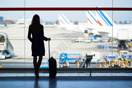 在国际机场旅行的年轻女性青年女旅客行李手提箱窗户航班飞机假期反射班级时间建筑图片