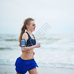 年轻健身女跑步在海滩上慢跑训练臀部工具海岸活动监视器运动海岸线肌肉女孩图片