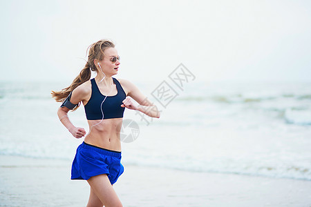 年轻健身女跑步在海滩上慢跑活动女孩海滨运动装有氧运动海岸成人臀部肌肉腰部图片