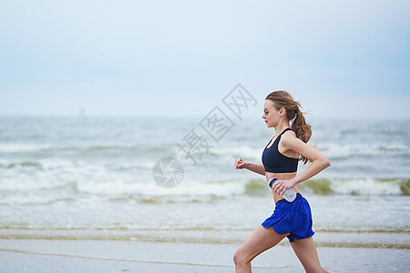 年轻健身女跑步在海滩上慢跑海岸线臀部胸罩肌肉女士速度训练活动运动蓝色图片