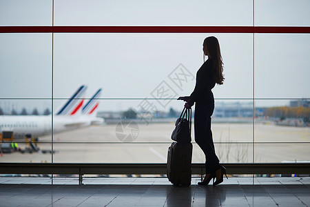 机场航班显示表机场的女人透过窗户看飞机背景