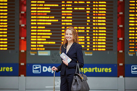 国际机场的年轻女性看着航班信息板 检查她的航班航空公司空姐线条手提飞机场成人木板商务套装游客图片