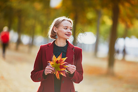年青的年轻女人 带着丰富多彩的秋叶阳光闲暇街道公园女性衣服森林外套理发树叶背景图片