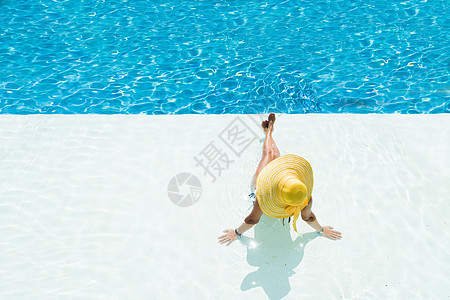 坐在泳池边缘的戴帽子的女人图片