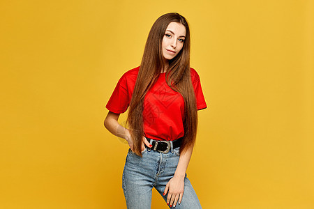 身穿红色白色白T恤衫和黄色背景孤立的牛仔裤的瘦瘦身年轻女子图片