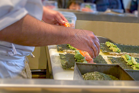 一个寿司厨师 给乌拉木做鳄梨和鲑鱼海鲜饮食男性柜台师傅美食海苔餐厅食物海藻图片