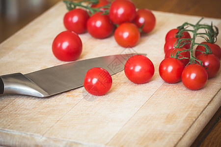 樱桃番茄和木切削板上的刀子藤蔓烹饪营养食物蔬菜砧板木头红色西红柿桌子图片