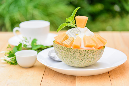 木桌上有甜甜冷凝固牛奶的环冰桌子甜瓜甜点美食派对食物冰淇淋浇头杏仁糖浆图片