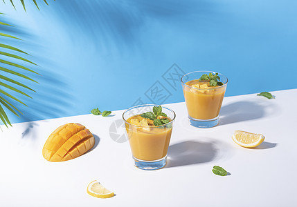 新鲜芒果冰淇淋和成熟的芒果切片 在彩色背景上 夏季饮料水果果汁薄荷乡村饮食液体异国食物玻璃叶子图片