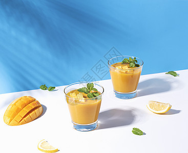 新鲜芒果冰淇淋和成熟的芒果切片 在彩色背景上 夏季饮料橙子食物热带液体薄荷蓝色情调水果叶子乡村图片