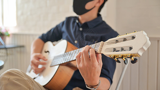 一个戴着面具在家里弹吉他 呆在家里的年轻人 W图片