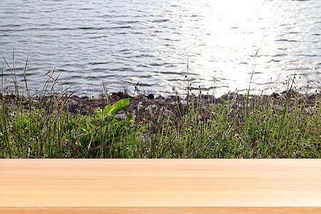 草地上的木板和河景中的地表水 山脉上的空木桌地板 木桌板前空的草地和天空早晨的阳光图片