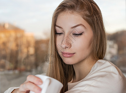 可爱的女孩正享受着杯子里的香味图片