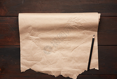黑铅笔和一卷木面上未织的棕色纸卷a木头古董笔记边界床单包装木板牛皮纸材料手稿图片