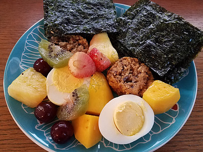 含芒果 鸡蛋 菠萝和海藻的木材表面蓝色板块水果午餐早餐奇异果小吃食物木头盘子桌子图片