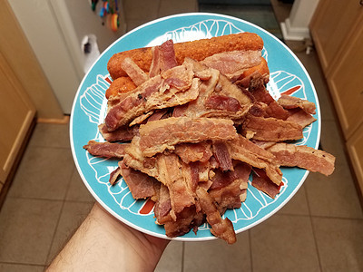 手拿着一堆培根肉和蓝盘上的鸡卷小吃盘子厨房美味食物猪肉蓝色图片