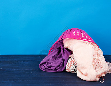 粉红色塑料篮 装满了衣服和蓝色背面的衬布衬衫粉色浴室纺织品琐事柳条家庭织物棉布洗衣店图片
