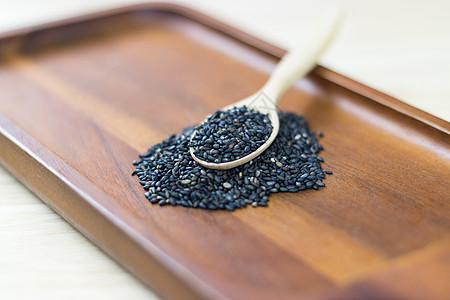 木桌上木勺堆放的黑芝麻种子食物香料烹饪谷物植物芝麻调味品白色节食勺子图片