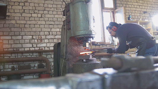熔化的金属在压力下通过一个宽角铁匠的手进行处理铁匠铺精神金工力量马蹄铁匠工作男人锤子燃烧制造业图片