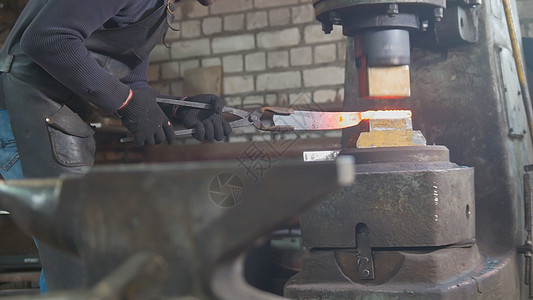 铁匠把红热铁钉在铁架上 自动锤打工业辉光金属金工制造业工艺火花工具店铺运动图片