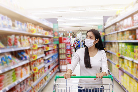 亚裔女性在超市戴面罩推车疾病杂货店女士杂货零售百货店铺隔离流感食物背景图片