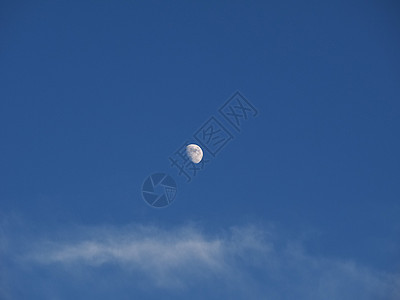 在蓝天上飘浮着的月亮背景图片