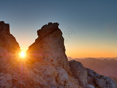 早晨太阳在山谷上阿尔卑斯山悬崖的沙石岩之间图片