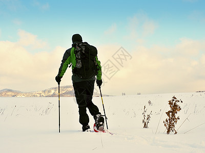 旅行者检查雪鞋 穿冬夹克和大背包的山顶雪中漫步场地男士爬坡粉雪手套鞋套漂移单身冒险曲目图片