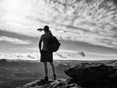 独自观光客与运动的背包站在悬崖边缘 看着深谷的蜂窝旅行男生游客享受导游顶峰男人短裤数字岩石图片