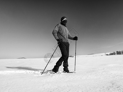 有雪鞋的观光客在雪地漂流中行走 阳光寒冷的天气运动护颈曲目远足晴天跨步手套冒险运动员荒野图片