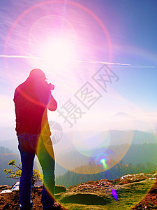 高个子正在用镜像摄影机拍摄脖子的相片 雪地岩石山峰阳光橙子风景顶峰积木相机公园太阳射线粉雪图片