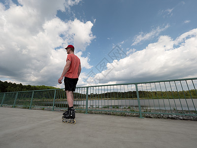 人骑着内线滑溜冰 乘着马车行驶 背面是天空身体低角度男性男人溜冰者爱好公园滚筒街道乐趣图片