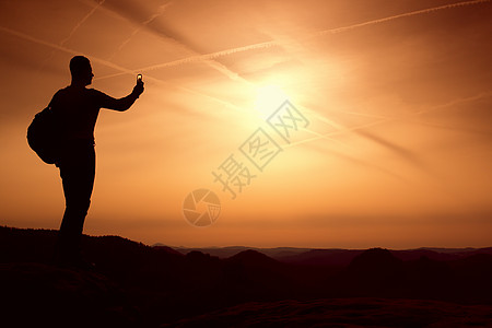 手持电话的高个背包机 山上春日运动男生幸福自由背包悬崖姿势游客顶峰远足者图片