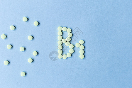 在蓝色背景上形成 B1 的黄色药片 复合维生素 概念 保健 健康营养 药品 健康的生活方式 食品添加剂 复制空间 软焦点 模糊的图片