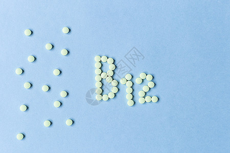 黄色药丸在蓝色背景上形成 B12 字母表的形状 复合维生素 营养 健康的生活方式 食品添加剂 复制空间 软焦点 模糊的背景红肉矿图片