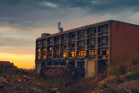 日落反映于废弃工业的破碎窗子中图片