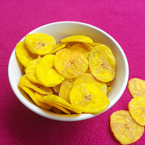 香蕉薯片保存在碗中 粉红色背景的美容筹码甜点黄色食物早餐薄荷桌子勺子营养果汁图片