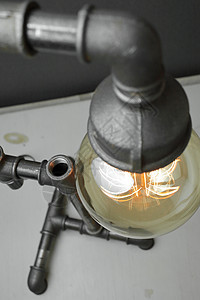 反向灯是由金属水管制成的 灰色背景有爱迪生灯 这个概念是一个好主意创造力管道古董玻璃白炽灯风格技术辉光灯泡想像力图片