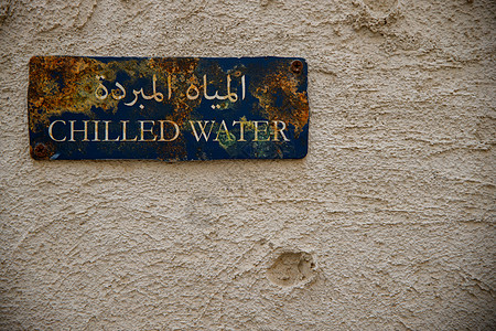 阿拉伯文写作可以读到传统阿拉伯房屋上一个生锈的蓝色标志上的“潮湿水”(Child Water)图片