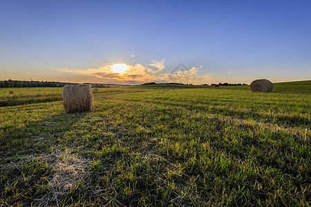一个日落时有堆叠的字段干草季节草地农业风景植物蓝色农场天空稻草图片